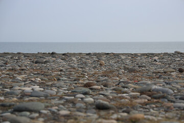 Pebbles and small stones on the shore of Black sea. Batumi, Georgia. Pebble rocks on beach. ocean sea water, round smooth stones. low angle view. coast vacations aesthetic. Seascape background