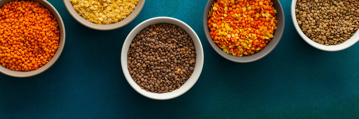 Multicolored lentils in bowls banner, yellow and brown, green and orange lentils, healthy legumes, top view, copy space