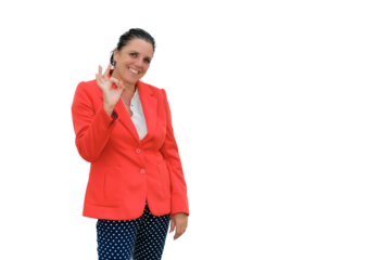 Older woman standing with fingers forming Ok sign, very smiling, on white background with red jacket. Sign language concept.