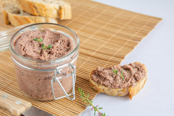 Vegan spread made with lentils and nuts on a rustic bread slice and in a glass jar, decorated with rosemary. Copy space on top. Vegan dipping.