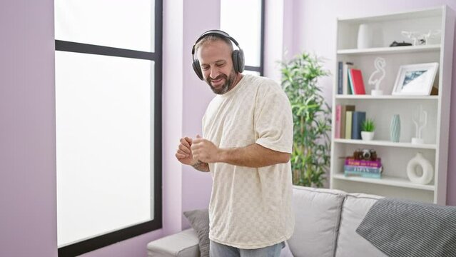 Cheerful young man at home, confidently dancing, beaming with joy as he listens to his favorite tune