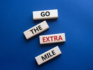 Go the extra mile symbol. Wooden blocks with words Go the extra mile. Beautiful deep blue background. Business and Go the extra mile concept. Copy space.