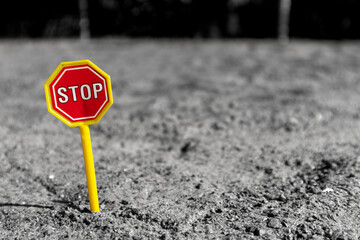 Toy road sign STOP in the middle of a sand field. Toy STOP sign on the sand. STOP road sign in a children's sandbox