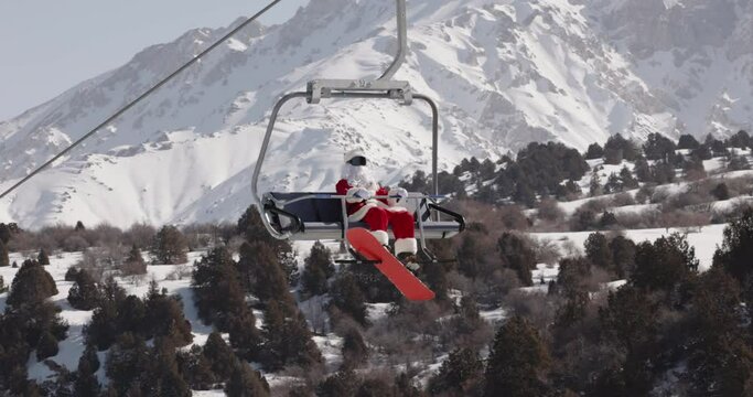 Santa Claus snowboarder in ski lift enjoys winter vacation. Winter sport outdoor activity. Christmas or New Year holidays