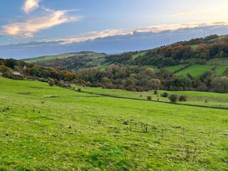 Fototapeta premium Autumn colours in, Shibden Valley, with sloping fields, farms, houses, and distant hills near, Halifax, UK