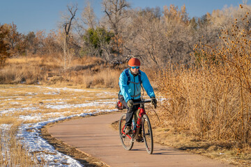 senior male cyclist is riding a touring gravel bike on a biking trail in Fort Collins, Colorado in cold fall weather with some snow