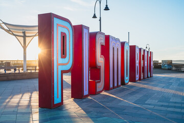 Pismo Beach Pier plaza at sunset. The large light-up letters, a new neon landmark of Pismo Beach city, California