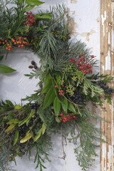 Christmas wreath of green branches and fruits of shrubs on the old white doors, fragment, fragment