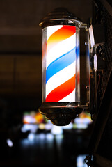 Barber pole of barbershop in the evening. Vertical photography.