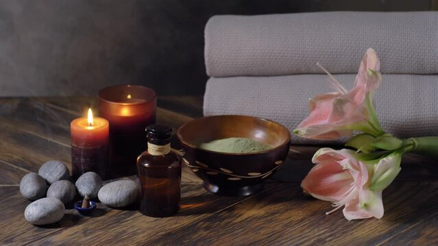 Beauty spa treatment with oil, laminaria algae in bowl and smoking incense cone on dark background