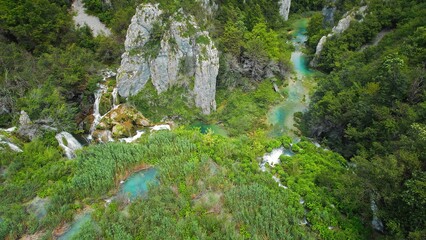 Plitvice waterfalls in mountain landscape of Croatia. Blue and green can be seen in the cascades. Water streams flow into a lake.