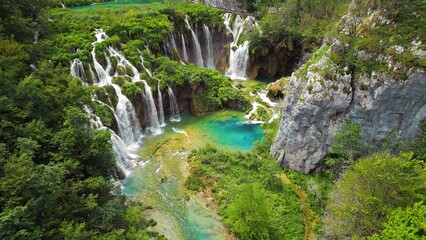 Fototapeta na wymiar Plitvice waterfalls in mountain landscape of Croatia. Blue and green can be seen in the cascades. Water streams flow into a lake.