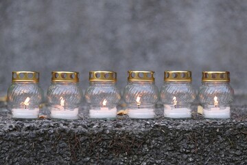 A row of lit white candles on a stone slab