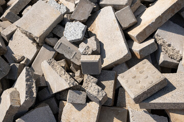 Shattered and broken street tiles, remnants of construction waste resulting from building demolition, have been placed in a construction waste container. A collection servic