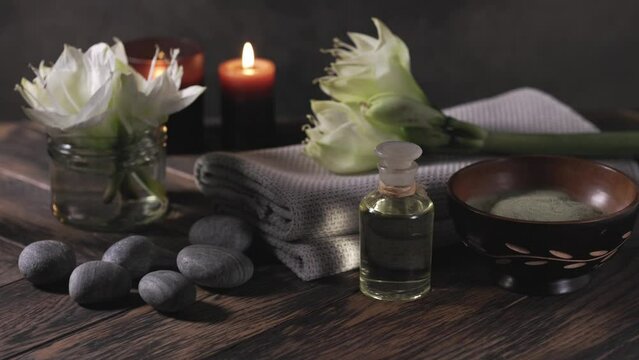 Beauty spa treatment with oil, laminaria algae in bowl and smoking aroma stick on dark background.