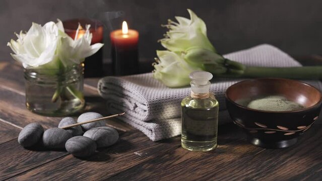 Beauty spa treatment with oil, laminaria algae in bowl and smoking aroma stick on dark background.