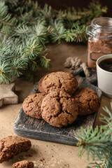 Homemade christmas chocolate cookies on wooden board and coffee on brown festive background with fir tree branches. Christmas holiday desserts