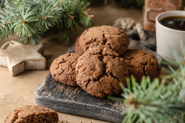Homemade christmas chocolate cookies on wooden board and coffee on brown festive background with fir tree branches. Christmas holiday desserts