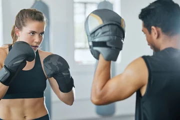 Foto auf Leinwand Boxing female boxer at gym with sports personal trainer practicing or training together for fight or match. Fitness and wellness coach teaching fit active athlete or client fighting exercise workout © Delcio Fernandes/peopleimages.com