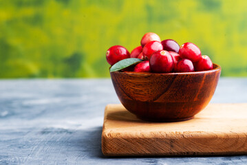 Fresh cranberries in a wooden bowl with spoon on dark wooden table. View from above.Space for text.