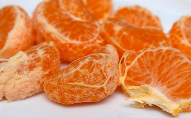 peeled tangerine on a white background. tangerine segments to be consumed. tangerine details. details of natural foods of plant origin. tangerine with selective focus.