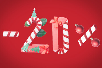 20% discount and a clearance sale composed of Christmas decoration, candy cane, red gift boxes and baubles. Creative concept. New year ornaments on the red background.