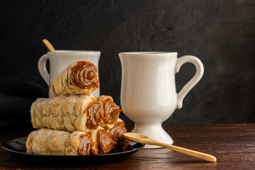 Composition of Argentine snack with cannon of dulce de leche and cup with infusion.