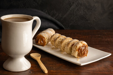 Composition of Argentine snack with cannon of dulce de leche and cup with infusion.