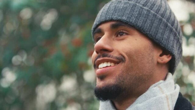 Close up portrait of smiling young man wearing woollen beanie hat and scarf on cold walk in misty autumn or winter countryside - shot in slow motion