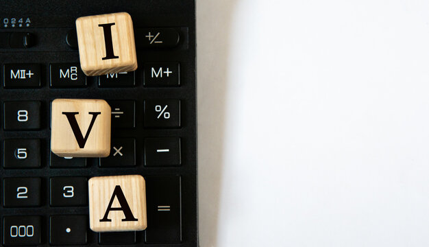 IVA - acronym on wooden cubes against the background of a calculator. Copy space