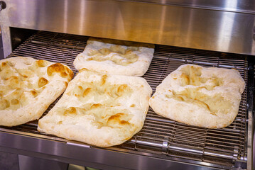 Parbake - known as the basis for Roman pizza. Baking the base for Roman pizza in a conveyor oven. Bakery bakes parbake