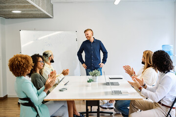 Colleagues congratulating a man after the presentation of a project