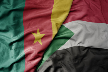 big waving national colorful flag of cameroon and national flag of sudan .