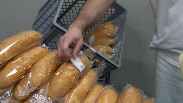 Bread Package Labeling at Bread Factory Production Line. Food Safety in Bakeries. Bakehouse Worker Works at Bread Packaging Line. Loaves of Bread Being Wrapped in Transparent Packaging.