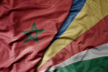 big waving national colorful flag of morocco and national flag of seychelles .