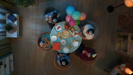 Top view of table with party food and drinks. Family with friends celebrating birthday, girl hugs toy bear that mom gave to her..