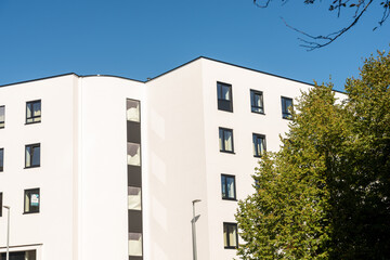 white building against the sky,Big white walls of the building under the blue sky and white clouds. Modern architecture. Minimalist design, architecture against the sky with a tree