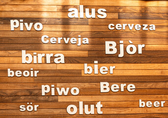 Obraz premium multi-language inscriptions of the word beer on a wooden background,The word beer printed in different languages,
