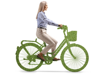 Young woman in formal clothes riding a bicycle made of grass