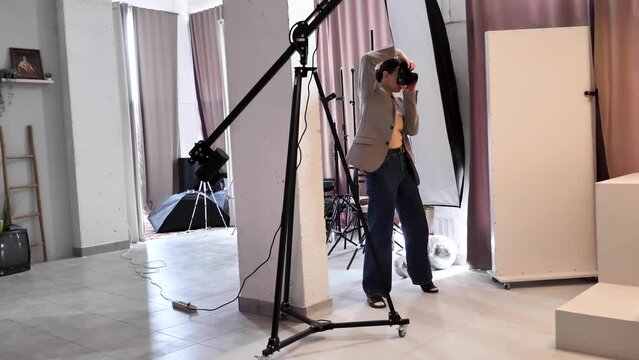 Female photographer taking pictures with a camera in a model photo studio. A modern popular profession.