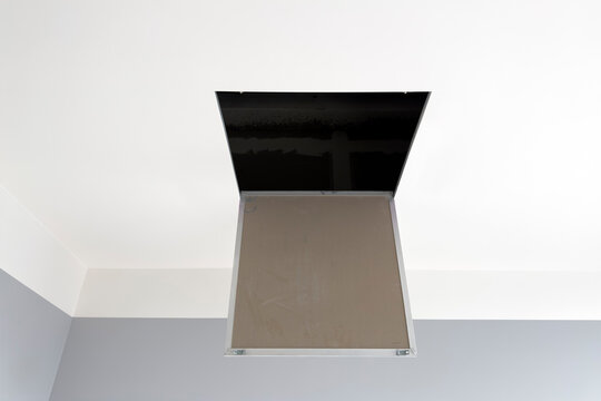 The hatch to the attic is hidden in the ceiling and painted in one color. Modern decoration and painting of the room, integrated hatch in the ceiling for the stairs to the attic.