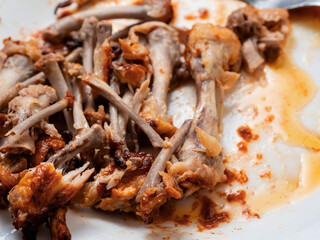 Pile of chicken wings bones on a white plate. Popular poultry product. Finished meal.
