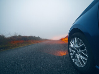Car on a small narrow country road with high quality asphalt surface without marking at fog....