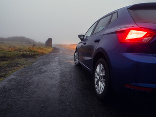 Car illuminating small narrow bridge in a country side, low visibility due to fog. Dangerous road...