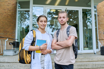 Portrait of two teenage friends, guy and girl outdoor, educational building