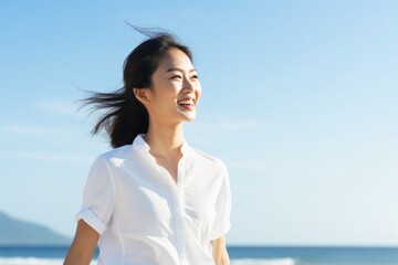 Asian woman walking on beach smiling happy