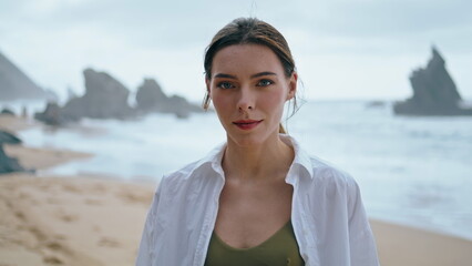 Pensive woman standing beach in white shirt closeup. Portrait of thoughtful girl