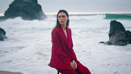 Tranquil woman sitting waves stormy ocean closeup. Girl in red suit posing beach
