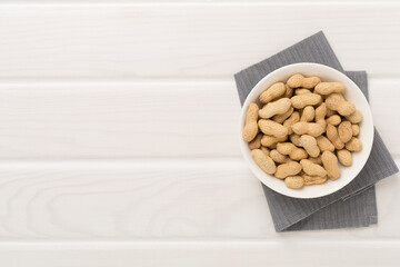 Unpeeled peanuts on wooden background, top view