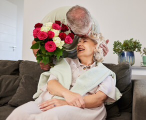 Couple kiss, senior and flowers for a birthday, love or celebration of marriage together. Happy, care and elderly man with bouquet for a woman in a home for a surprise, date or gift for anniversary